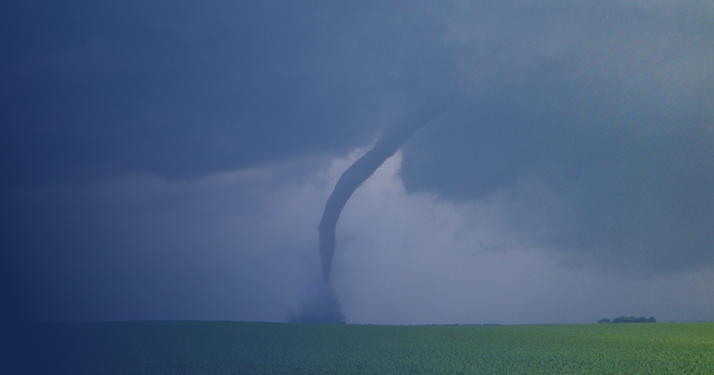Tornado touching down over rural farmland beneath a dark stormy sky