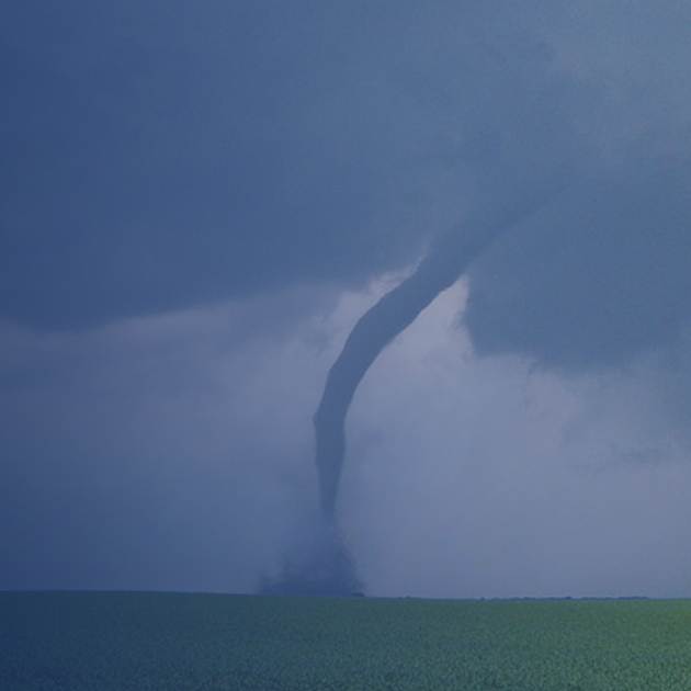 Tornado touching down over rural farmland beneath a dark stormy sky